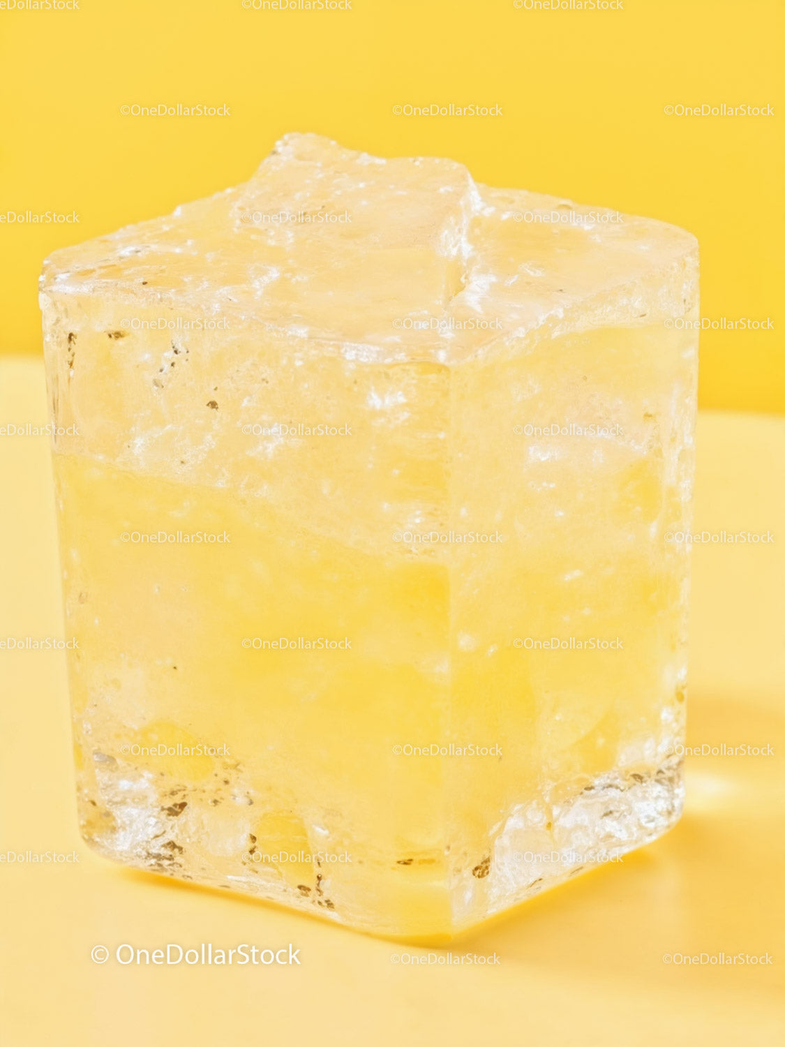 Close up of melting ice cube on yellow surface