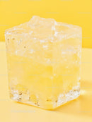 Close up of melting ice cube on yellow surface
