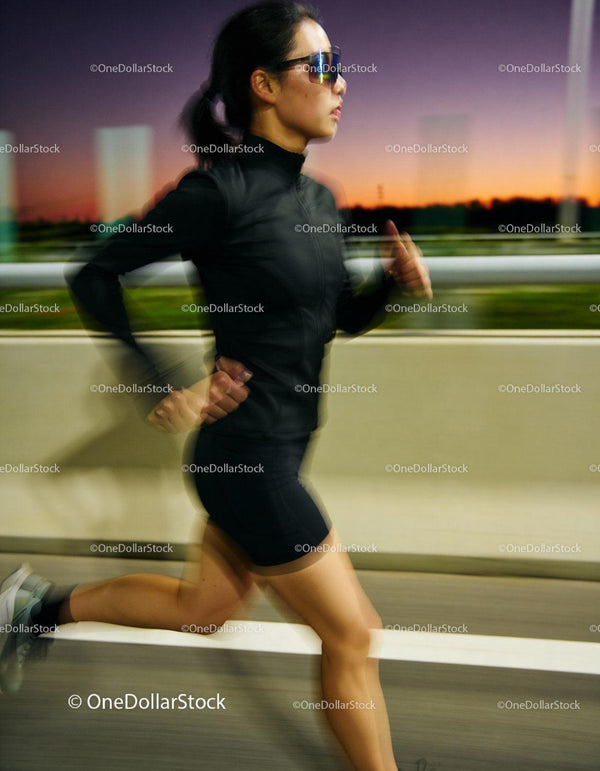 Active woman jogging outdoors at dusk in athletic wear