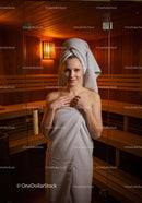 Relaxing Woman in Towel in Sauna Spa Room with Wooden Interior