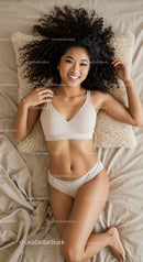 Smiling young woman relaxing on bed with curly hair
