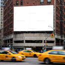 Busy street corner with yellow taxis and blank billboard