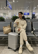 Young Woman Traveling at Airport with Suitcase and Coffee