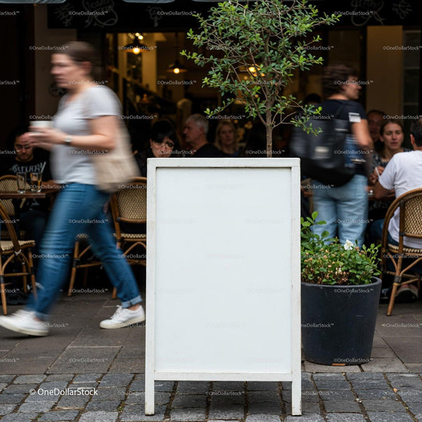 Empty sidewalk signboard outside busy cafe with walking pedestrians JPG Mockup Image