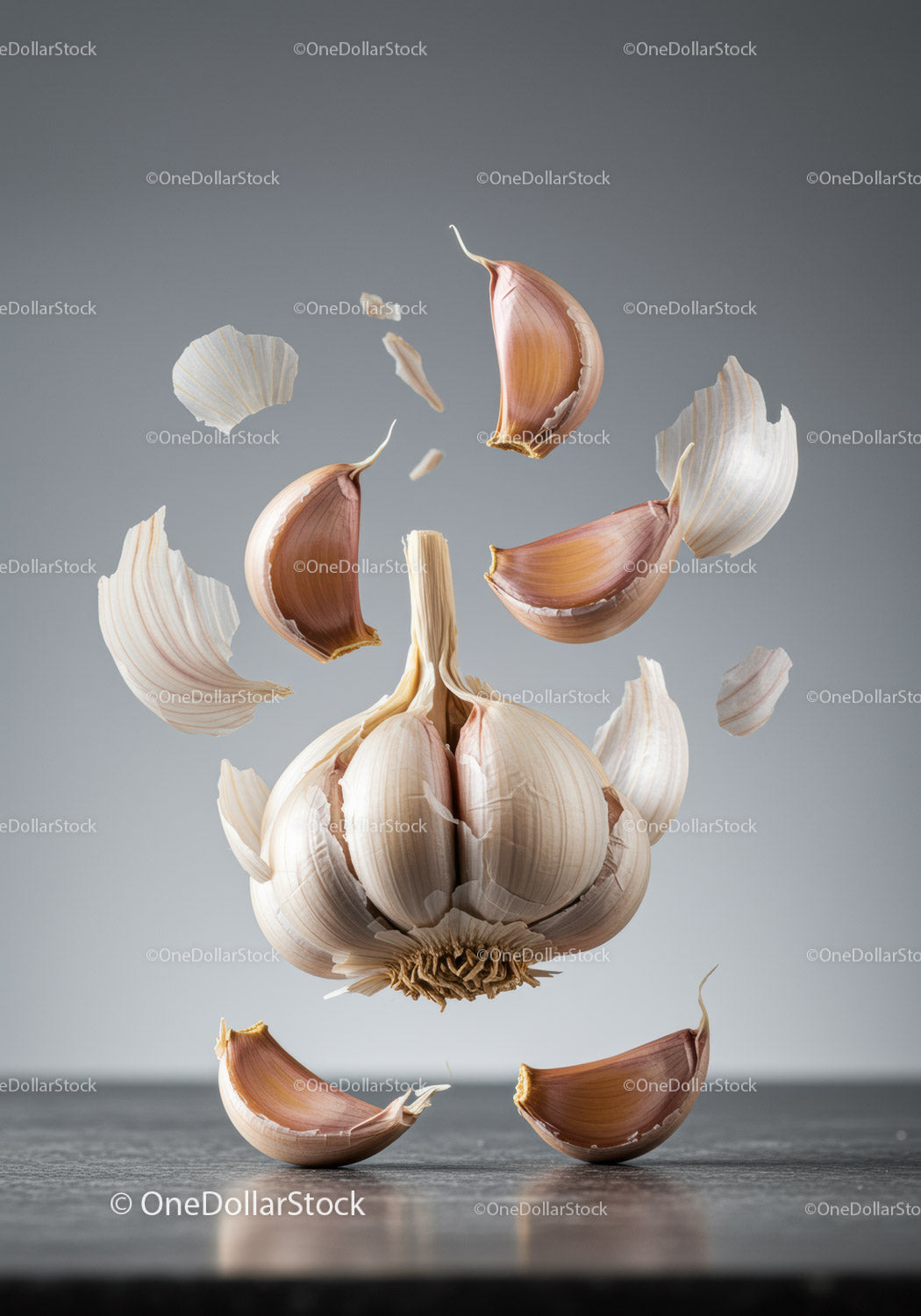Floating garlic cloves with peeling skin on gray surface