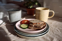 Coffee Mugs with Sliced Bread and Fresh Vegetables on Table