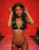 Fashionably Dressed Woman in Black Bikini with Jewelry Against Red Background