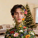 Young man surrounded by vibrant flowers in cozy living room