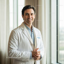 Male Doctor Smiling in Hospital Ward with Bright Natural Light