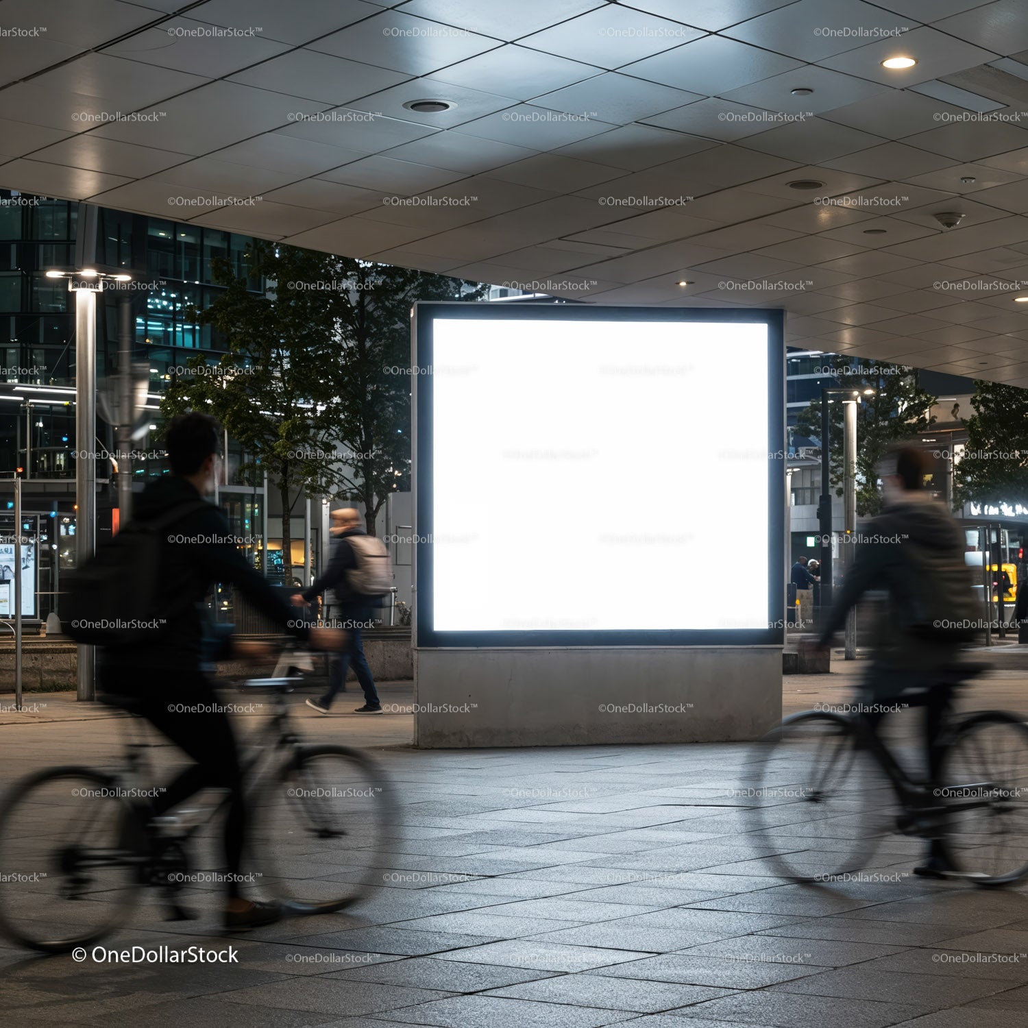 Urban night scene with illuminated blank billboard and cyclists
