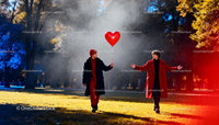 Two men sharing a heart balloon in an autumn park