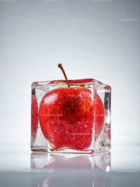 Fresh red apple frozen inside a clear ice cube