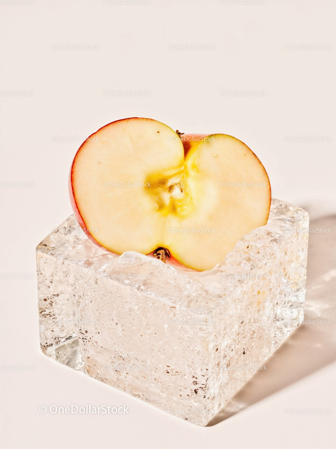 Fresh apple half resting on transparent ice cube