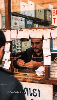 Man Counting Coins at a Traditional Money Exchange Window