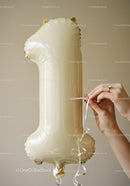 Hands tying ribbon on gold number one balloon
