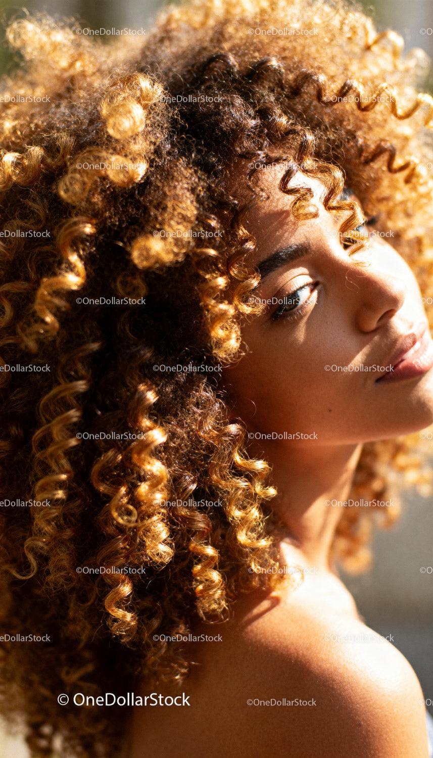 Close-up of woman with golden curly hair in sunlight