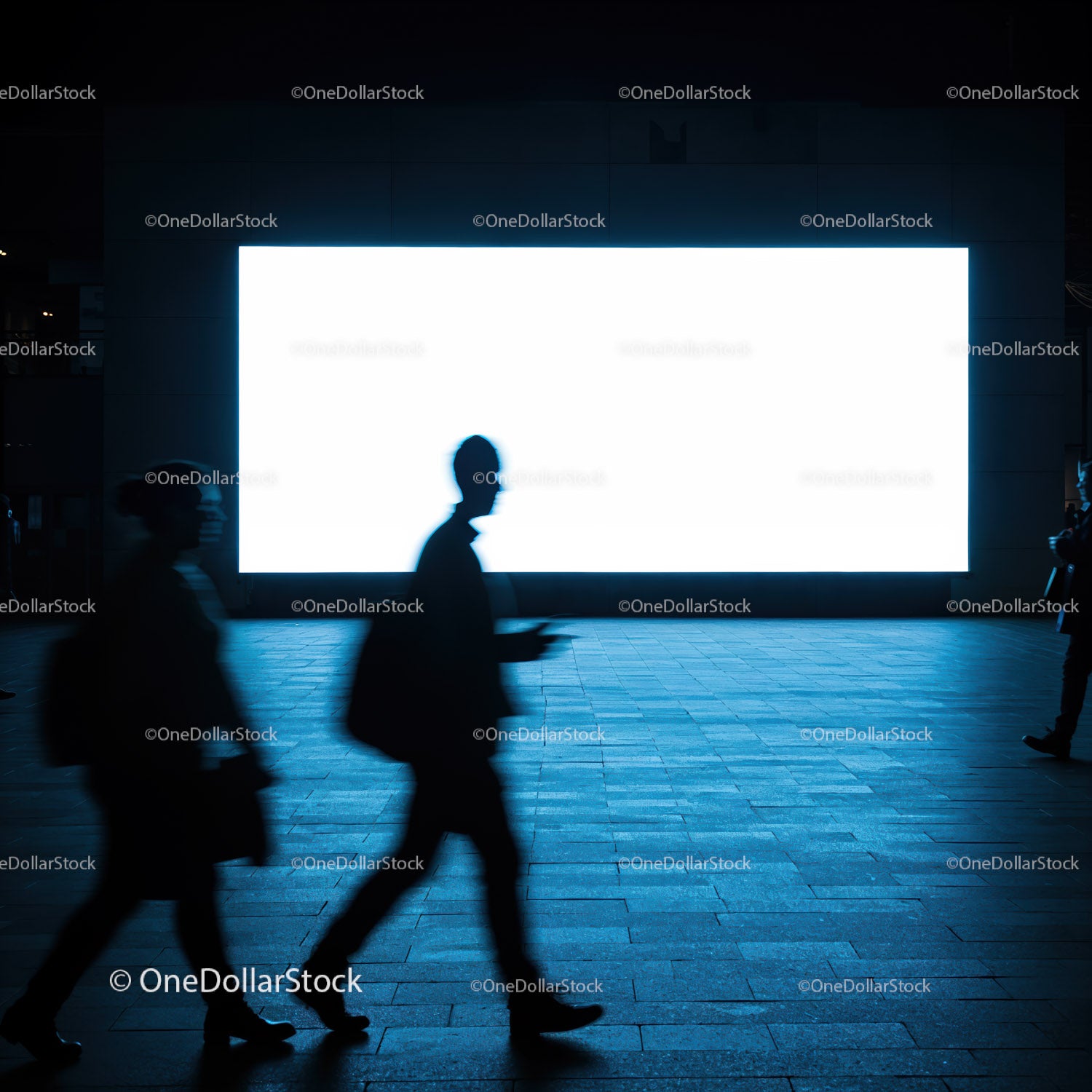 Silhouettes walking past bright urban billboard at night