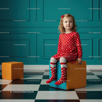 Toddler girl in red dress sitting on colorful cube