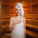 Young Woman Relaxing in Sauna with Towel Wrap and Wooden Interior