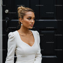 Elegant woman in white dress standing by dark door