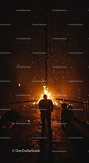 Silhouettes gathered around a bright night bonfire