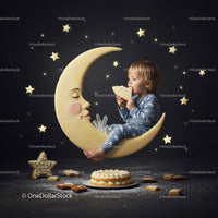 Toddler in pajamas nibbling cookie on crescent moon