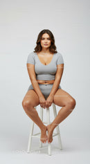 Young Woman Sitting on a White Chair in Casual Gray Outfit