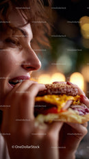 Close-up of Woman Eating Juicy Cheeseburger in Night Scene