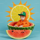 Child in Orange Hoodie Sitting Inside Watermelon Bowl