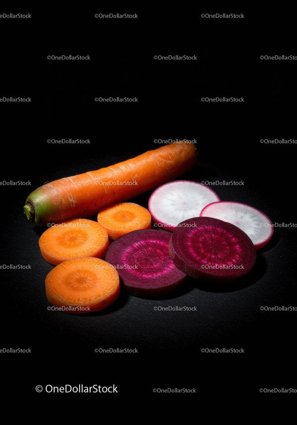 Fresh Sliced Colorful Root Vegetables on Black Surface