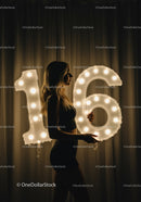 Young woman celebrating sweet sixteen with illuminated balloons