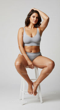 Confident Woman in Grey Lingerie Sitting on a White Stool Studio Portrait