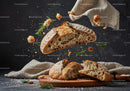 Fresh rustic bread breaking with scattered crumbs and herbs