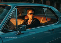 Stylish Man in Suit Sitting in Vintage Blue Car with Sunset Lighting