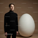 Calm young man standing near oversized white egg