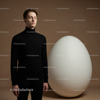 Calm young man standing near oversized white egg