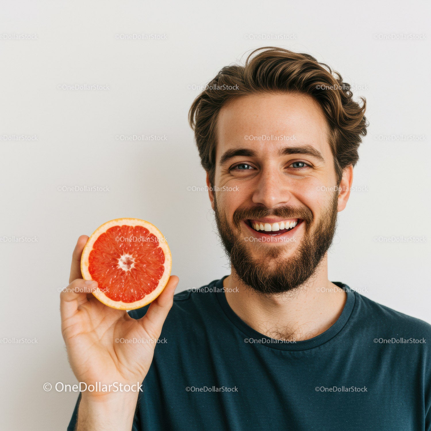 Young Smiling Man Holding Juicy Pink Grapefruit Slice in Bright Room