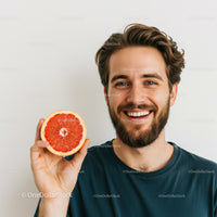 Young Smiling Man Holding Juicy Pink Grapefruit Slice in Bright Room