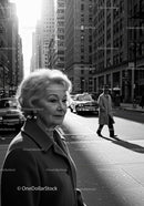 Elderly Woman in Busy City Street Surrounded by Vintage Cars