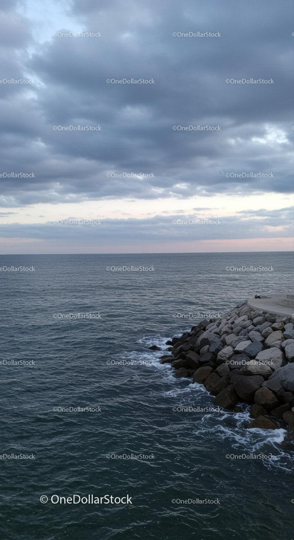 Stormy Sky Over Calm Ocean with Rocky Shore