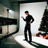 Young man posing by Christmas tree in studio setting