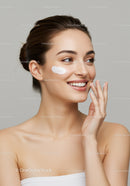 Fresh Smiling Woman Applying Cream on Cheek for Glowing Skin