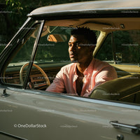 Young Man in Pink Shirt Sitting in Vintage Car on a Sunny Day