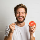 Young Man Smiling While Holding Juicy Grapefruit for Refreshing Lifestyle