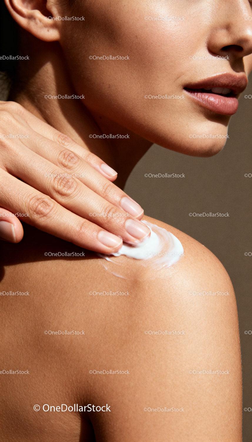 Woman applying moisturizing cream on smooth shoulder
