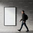 Man walking past blank poster on concrete wall