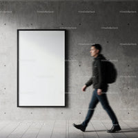 Man walking past blank poster on concrete wall