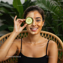 Woman with Face Mask Holding Cucumber Slice in Tropical Setting