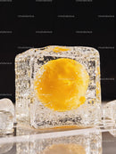 Yellow fruit frozen inside clear ice cube detail