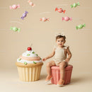 Toddler Sitting Next to Giant Cupcake with Candy Mobile